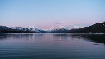 Un lago tranquilo con montañas nevadas al fondo.