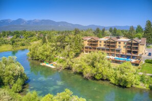 Un hotel de varios pisos con piscina y un río al frente.