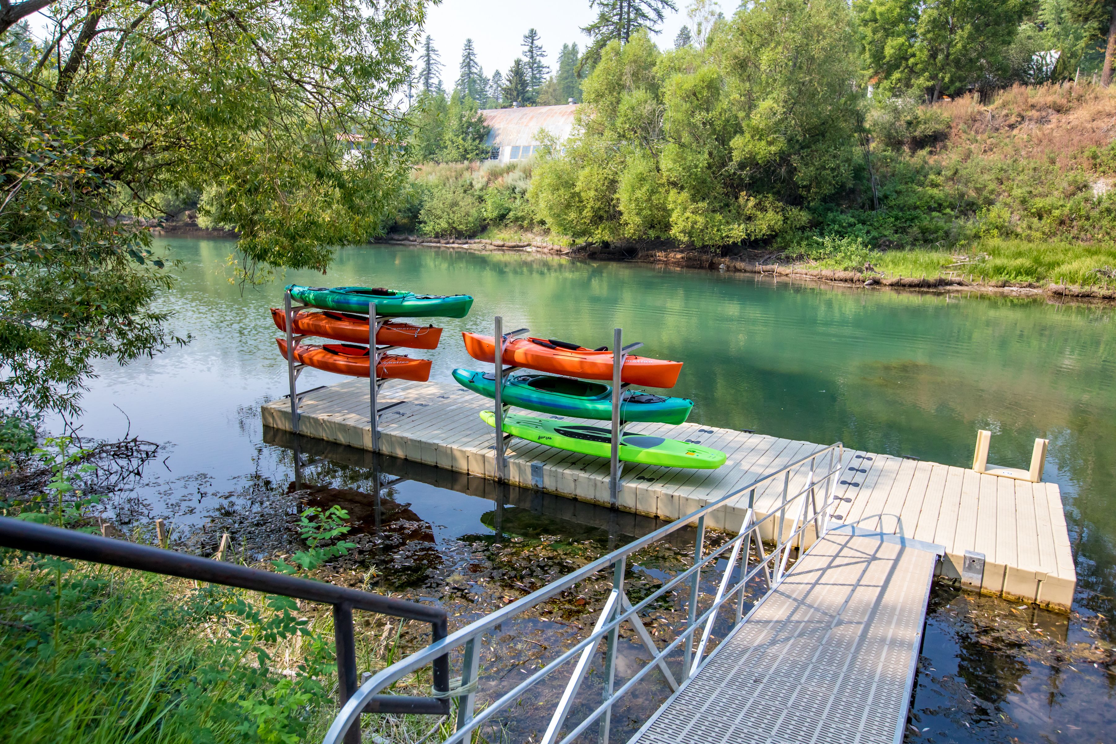 Een houten steiger met kajaks en een metalen hekwerk.