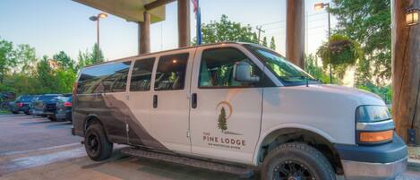 Ein weißer Van mit dem Schriftzug "The Pine Lodge" steht unter einer Überdachung.