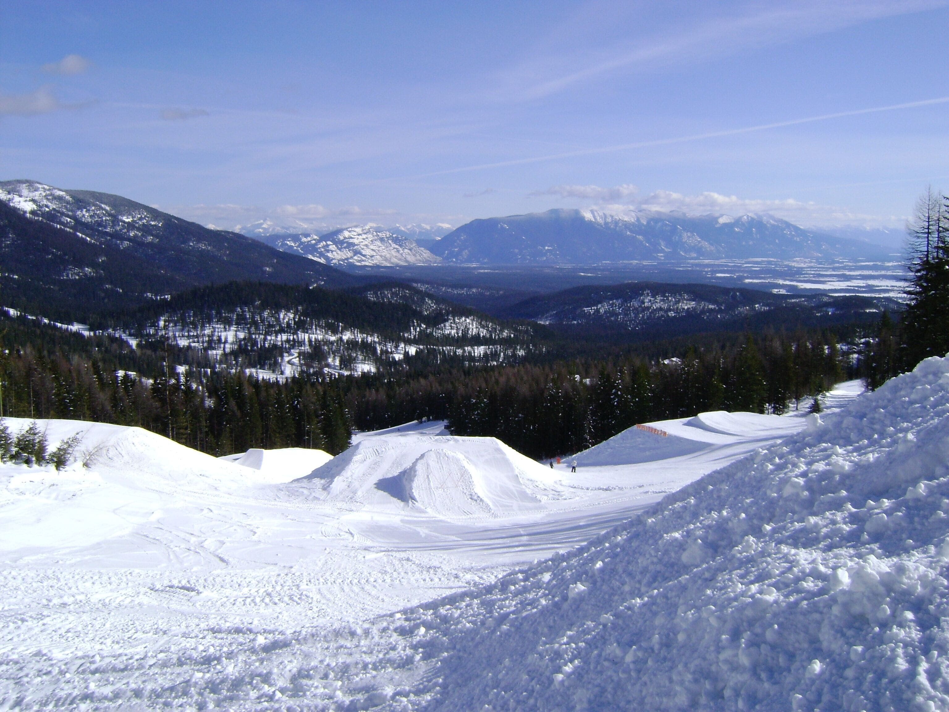 Un paisaje montañoso nevado con una pista de esquí.