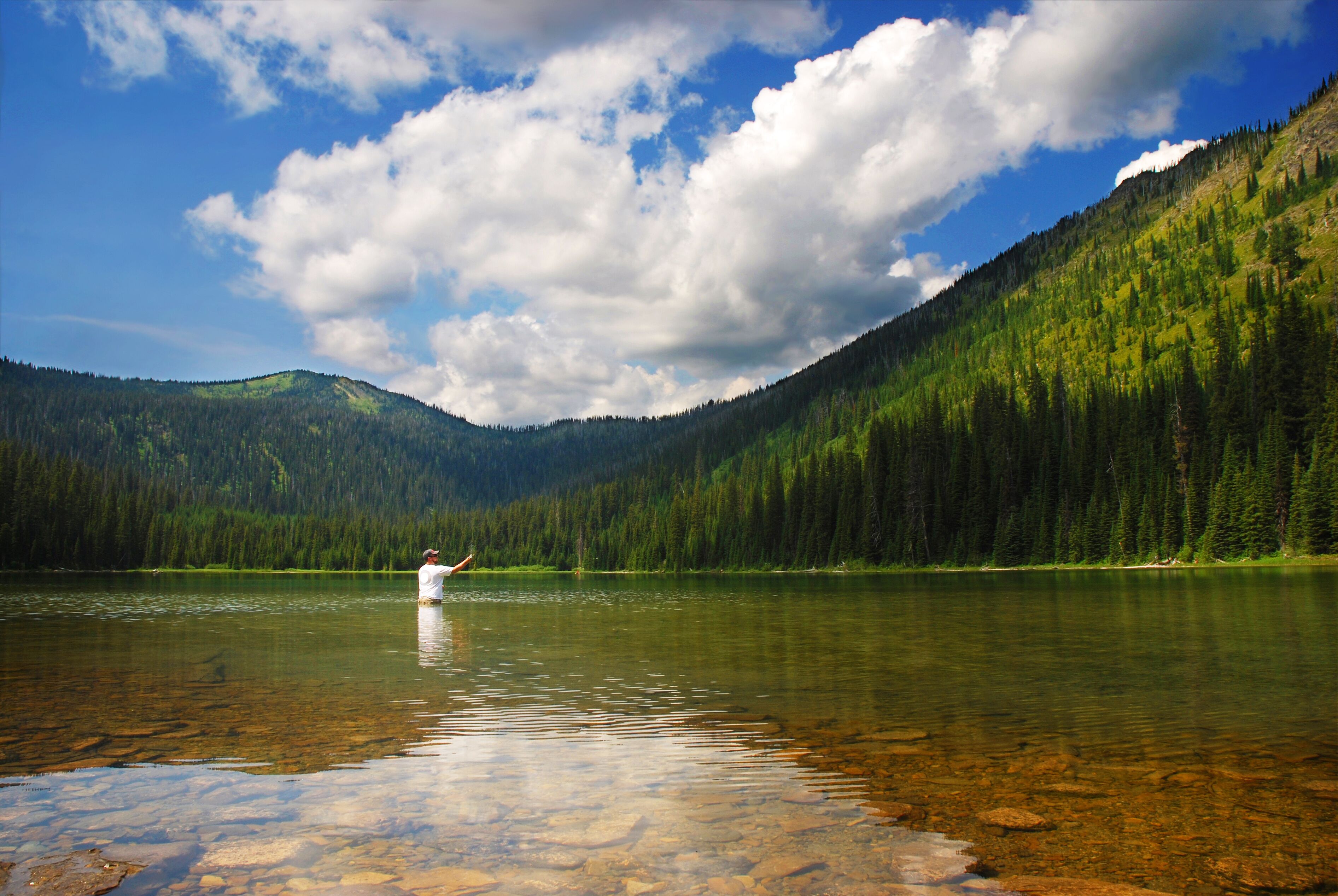 A clear lake surrounded by forested mountains.