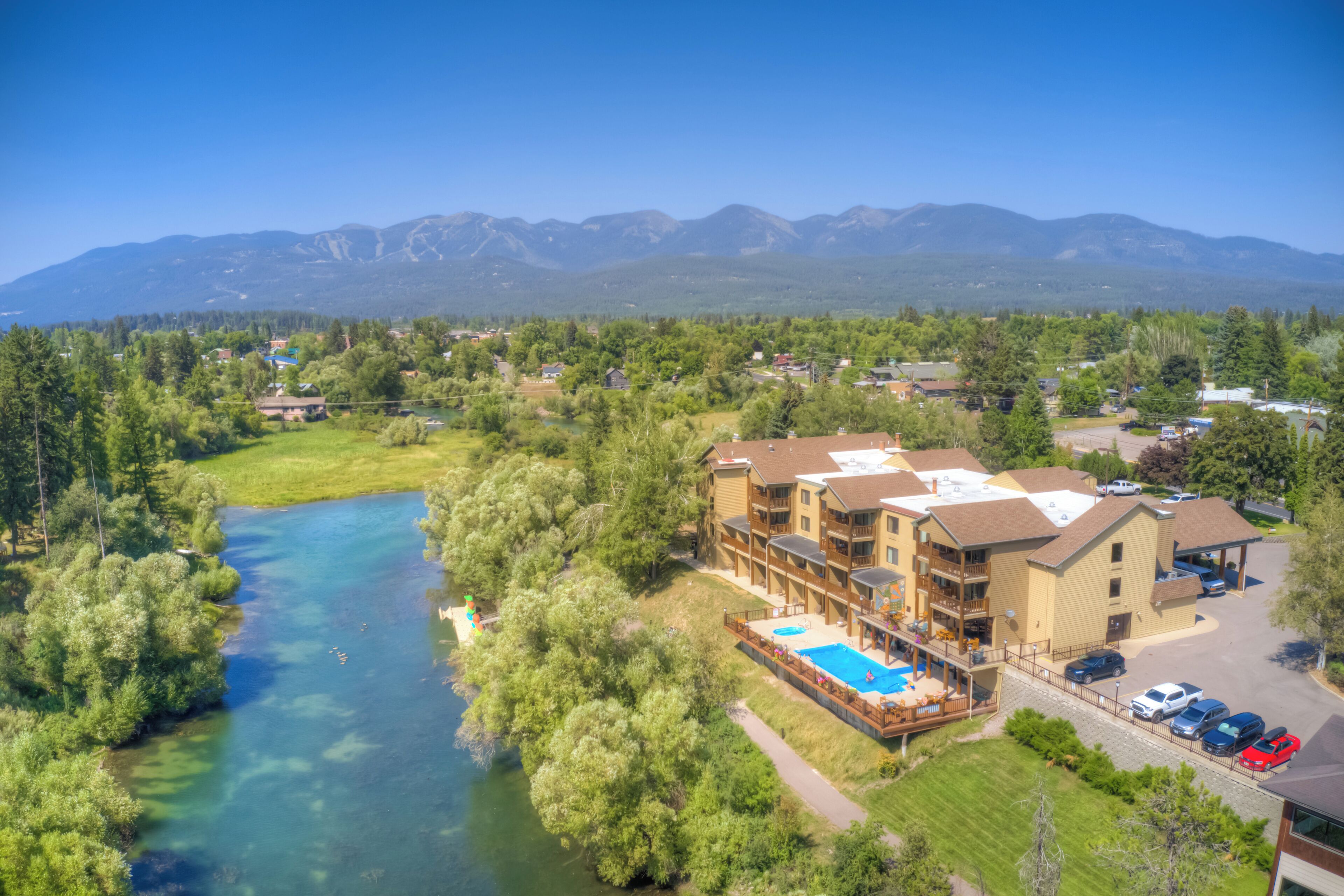 A resort with a swimming pool, a parking area, and a river.