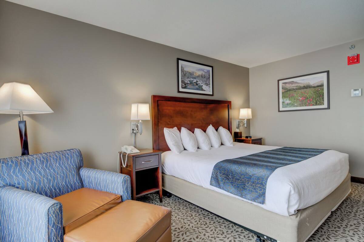 Hotelkamer met een groot bed, een bank, een nachtkastje met een lamp en twee ingelijste foto's aan de muur.