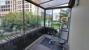A balcony with a view of a cityscape, a treadmill, and a small outdoor area with a bench. - Viaggio Teleport Suites (Bogotá)