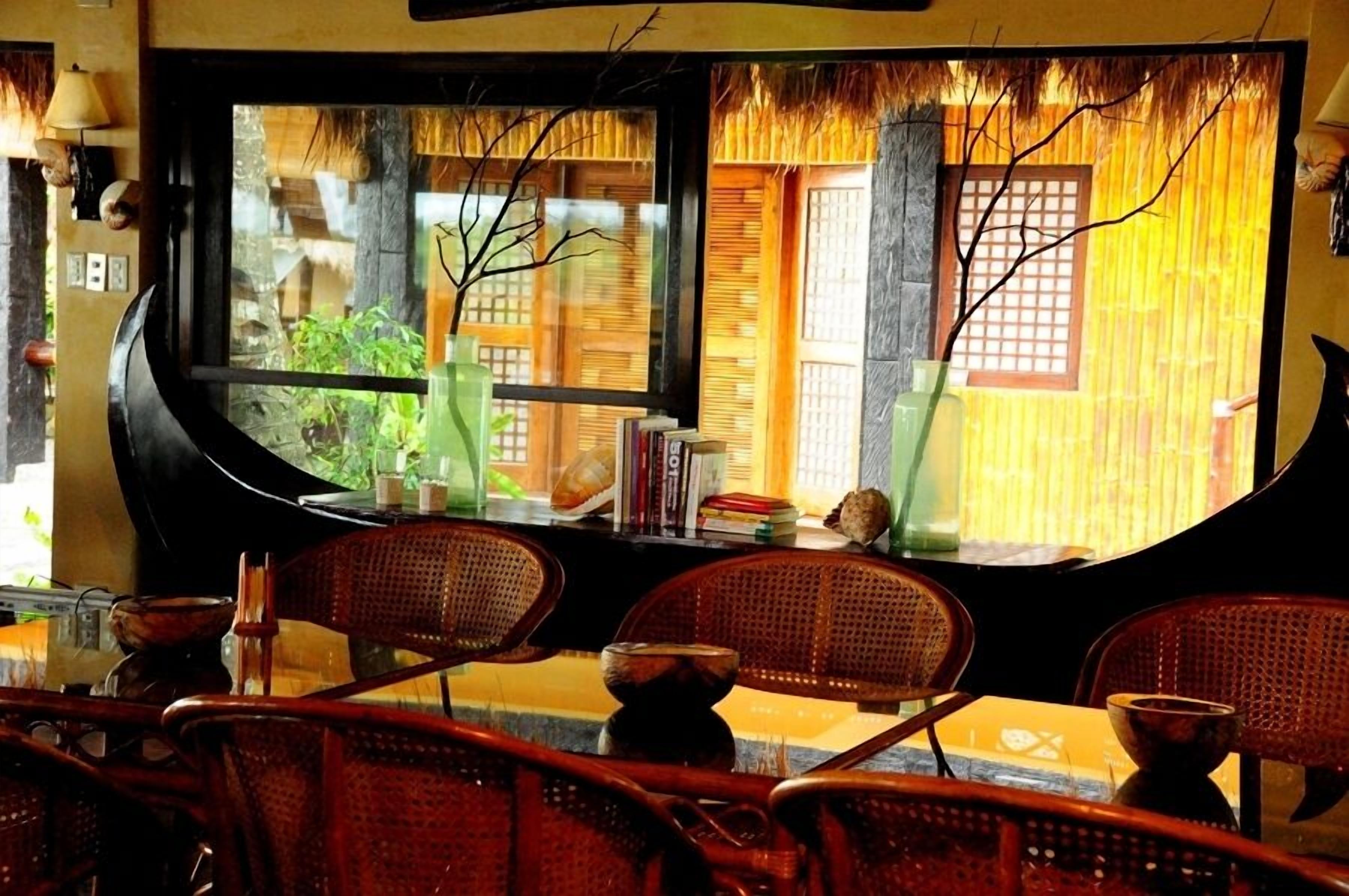 A room with a large window, wicker chairs, a small table, and a decorative vase.