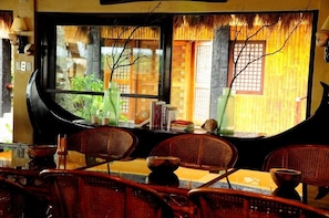 A room with a large window, wicker chairs, a small table, and a decorative vase.