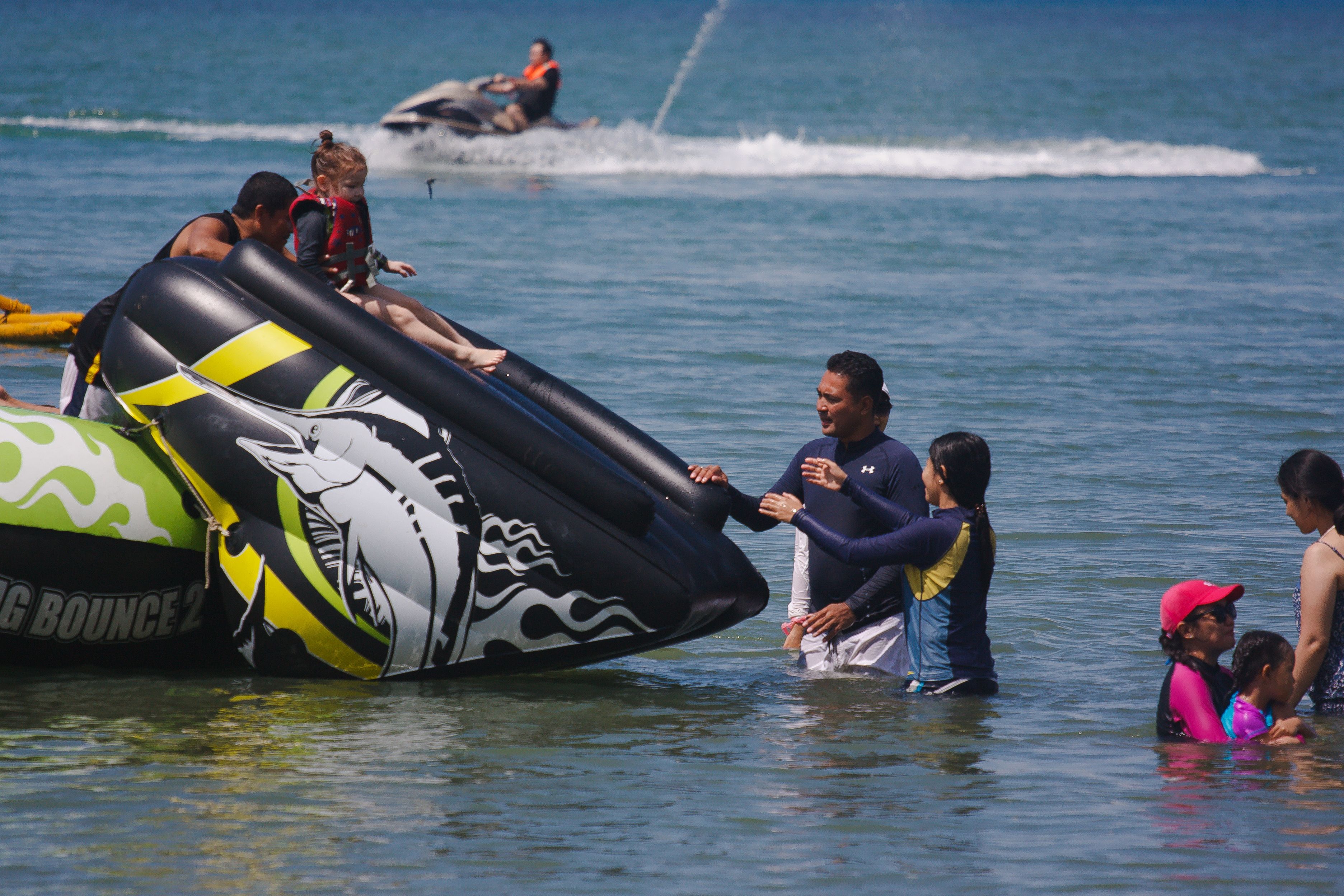 A water activity area with inflatable structures and people engaging in water sports.