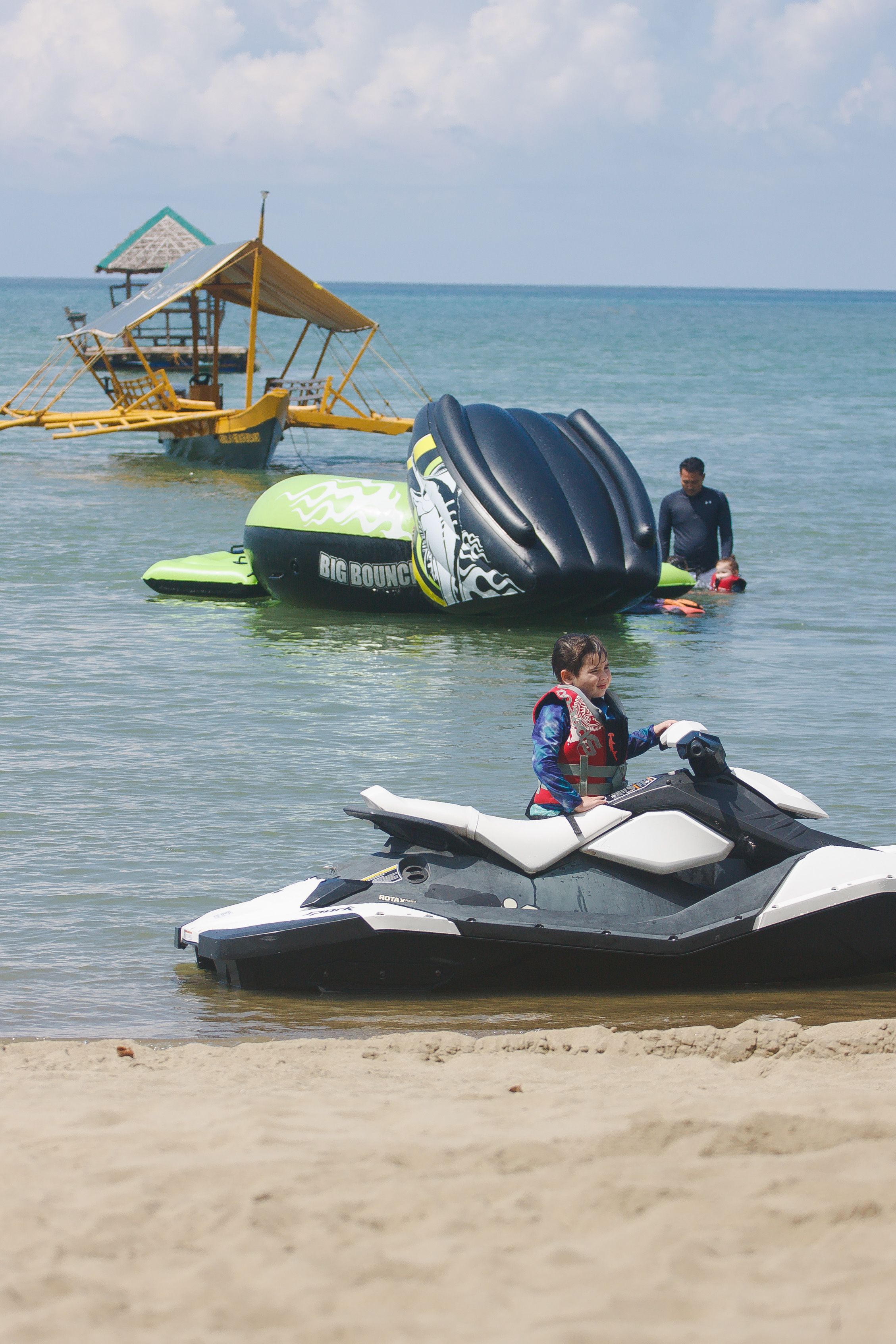A beach with a jet ski and a floating structure in the water.