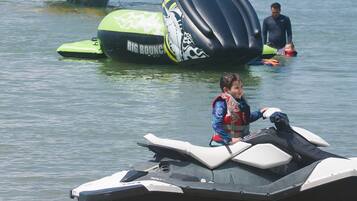 A beach with a jet ski and a floating structure in the water.