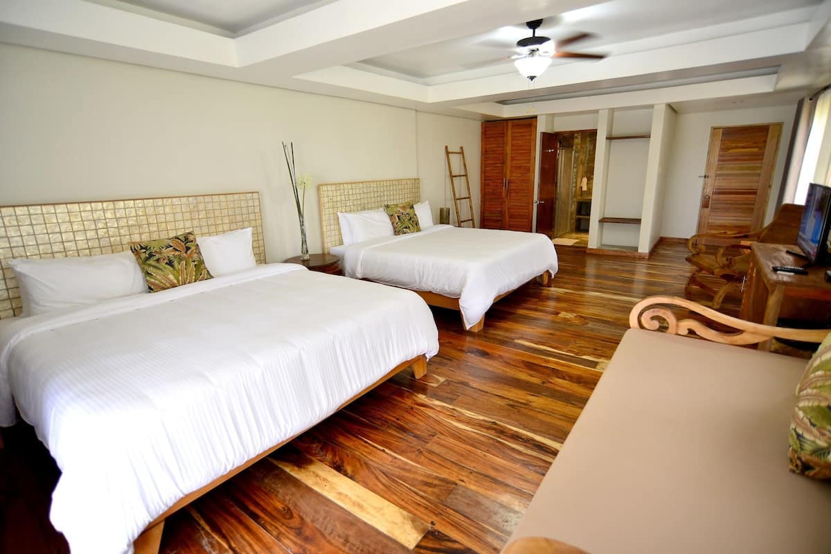 Une chambre d’hôtel avec deux lits, un plancher en bois, une télévision et une armoire en bois.