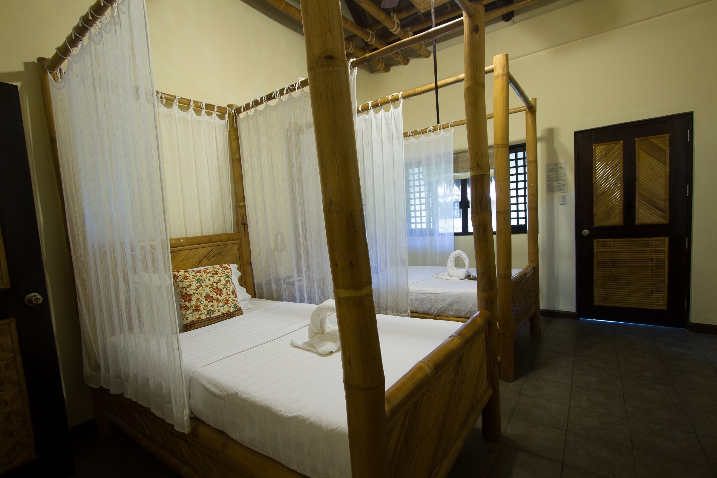A four-poster bed with white linens and a floral pillow, a wooden headboard, and a canopy.