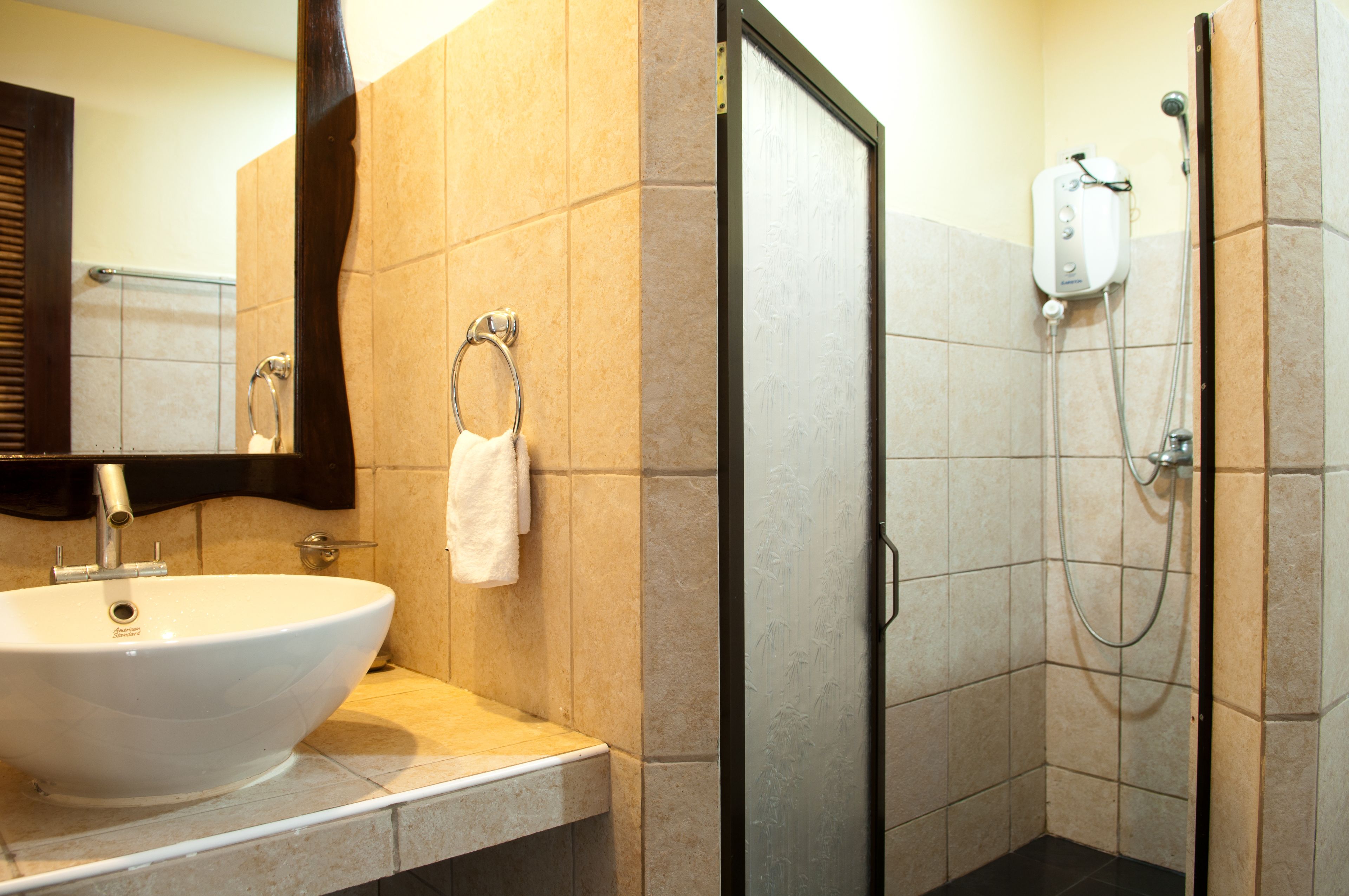 Un baño con lavamanos blanco, un aro para toallas y una ducha con cabezal de ducha manual.