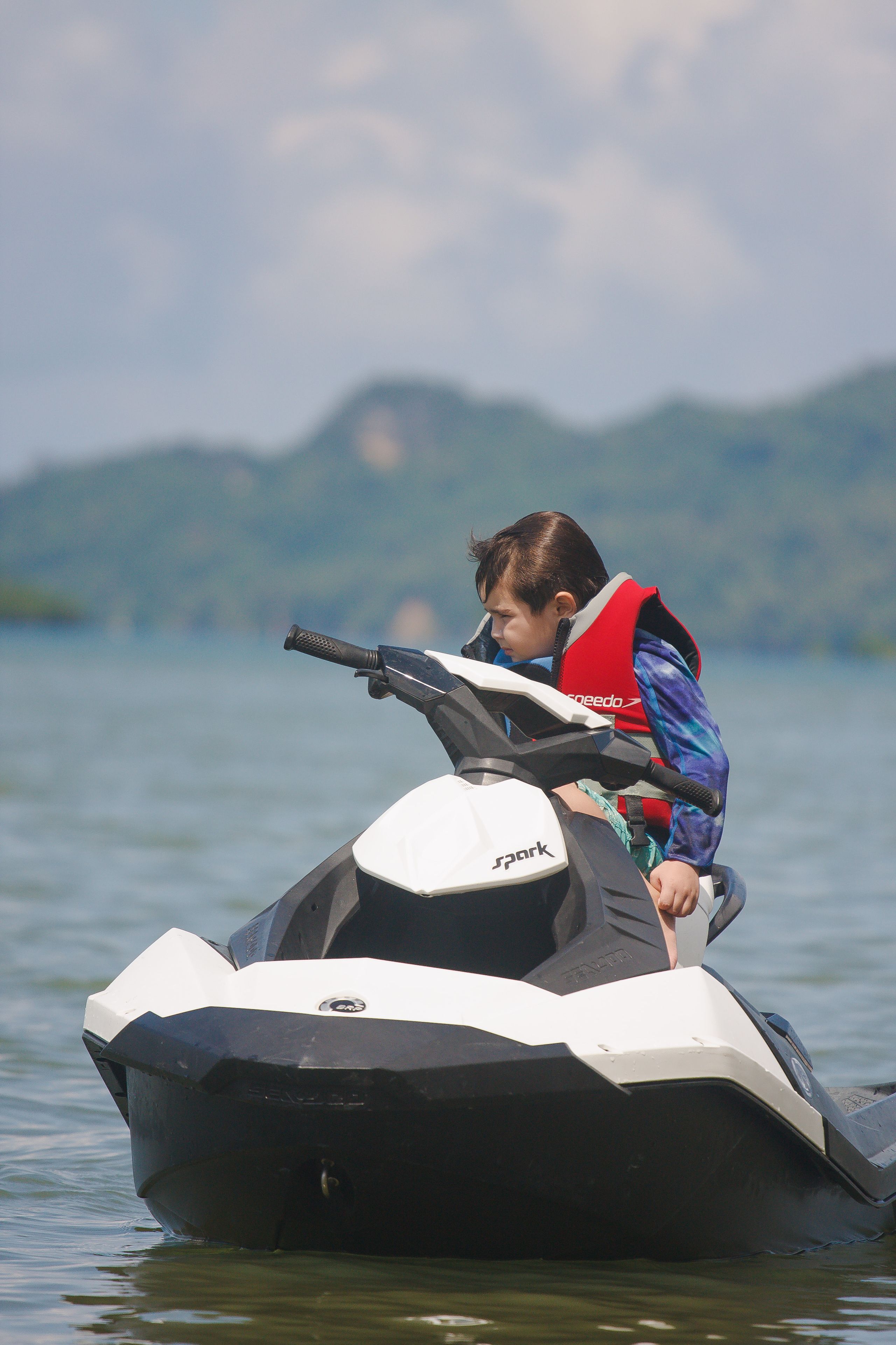 A person riding a jet ski on a body of water with mountains in the background.