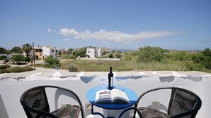 A terrace with a table and chairs, overlooking a residential area with houses and greenery. - Sunny Beach Studios (Naxos)