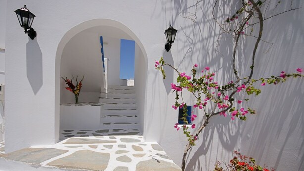 A white-walled building with a stone pathway leading to an archway. - Sunny Beach Studios (Naxos)