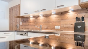 A modern kitchen with wooden accents, a built-in dishwasher, and a knife block on the countertop. - A CASA Saphir (Soelden)