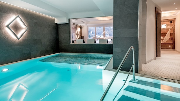 A modern indoor swimming pool with a clear view of the adjacent spa area. - A CASA Saphir (Soelden)