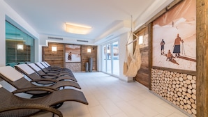 A spa area with wicker lounge chairs, wooden walls, and a large poster of a mountain scene. - A CASA Saphir (Soelden)