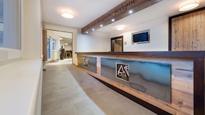 A reception area with a wooden reception desk, a TV mounted on the wall, and a sign indicating the reception area. - A CASA Saphir (Soelden)