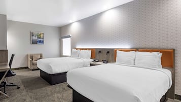 A hotel room with two beds, a desk, and a chair.