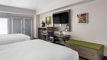 Habitación de hotel con dos camas, un escritorio con computadora, televisor y microondas.
