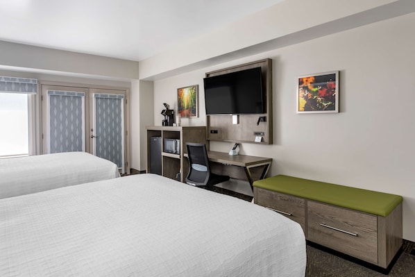 A hotel room with two beds, a desk with a computer, a TV, and a microwave.