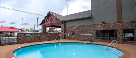 A swimming pool with a lifeguard tower, a covered area, and a stone wall.
