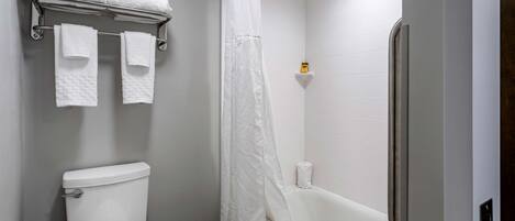 Un baño con inodoro, bañera y cortina de ducha.