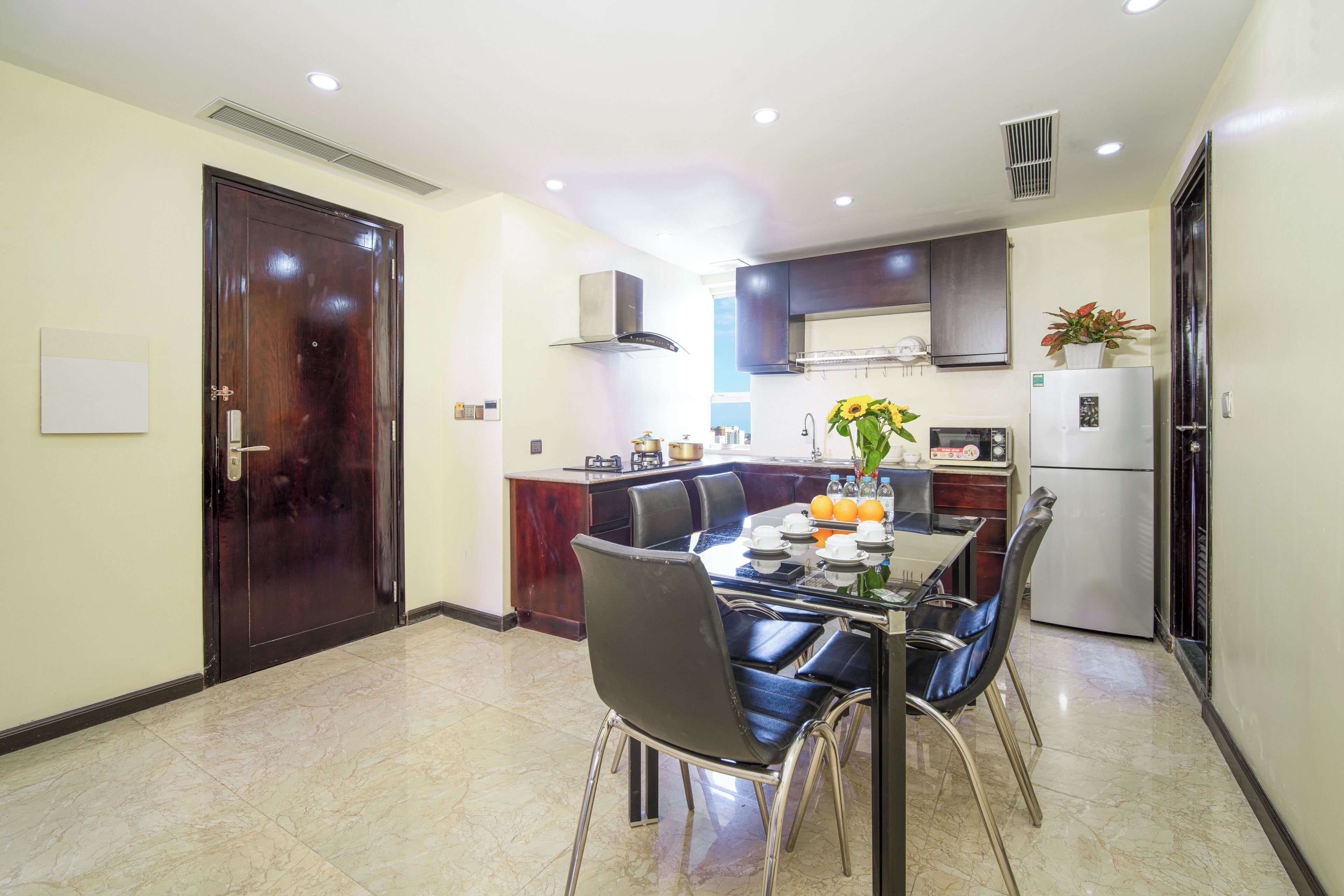 Una cocina moderna con armarios oscuros, una isla central y una zona de comedor con mesa y sillas.
