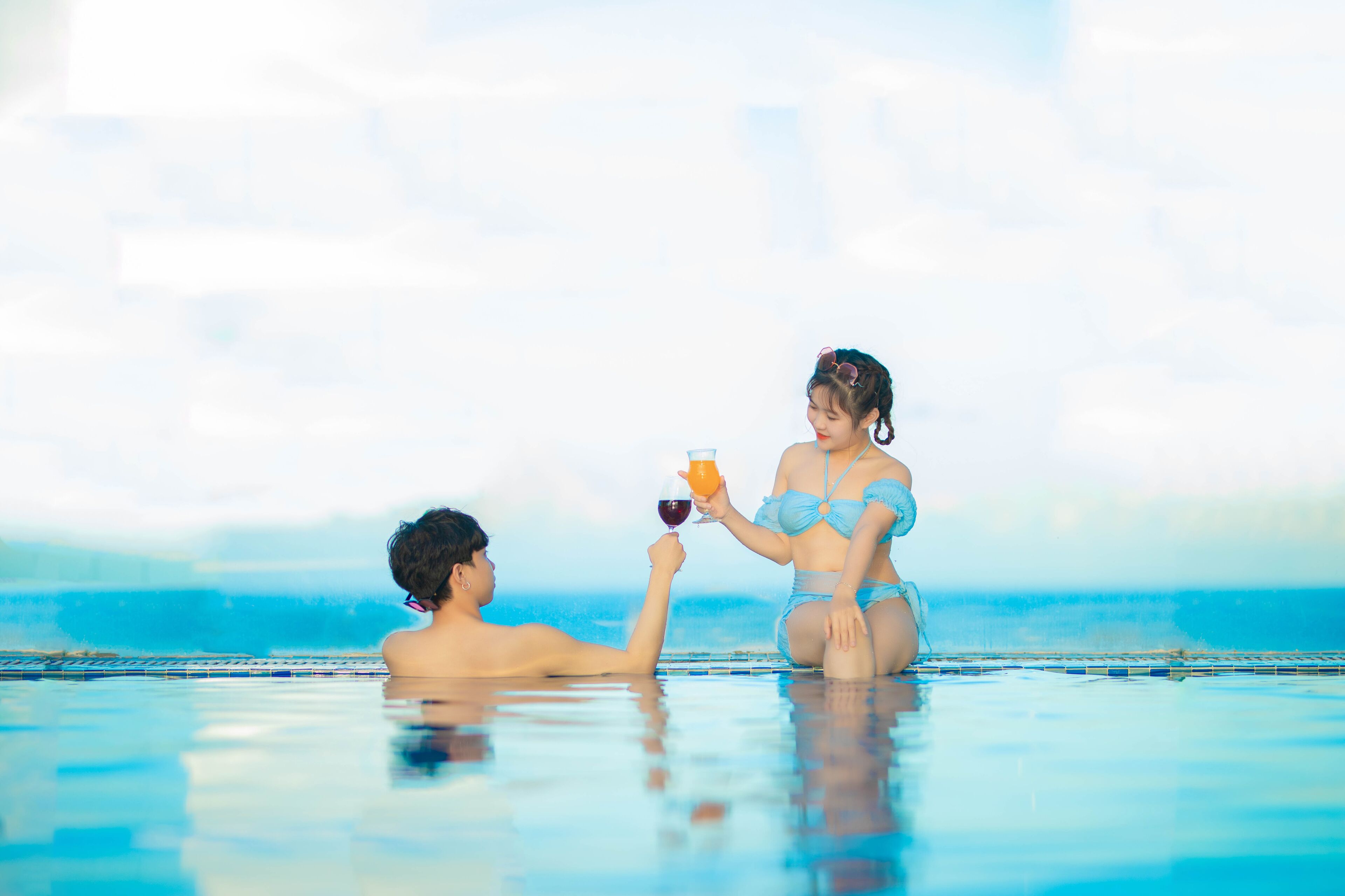 A couple in a swimming pool with a clear view of the ocean in the background.