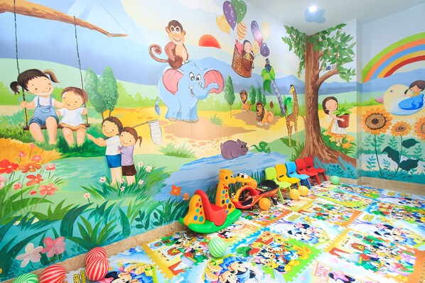 Une chambre d’enfant pleine de vie, avec une fresque murale, un espace de jeux coloré et une grande variété de jouets.