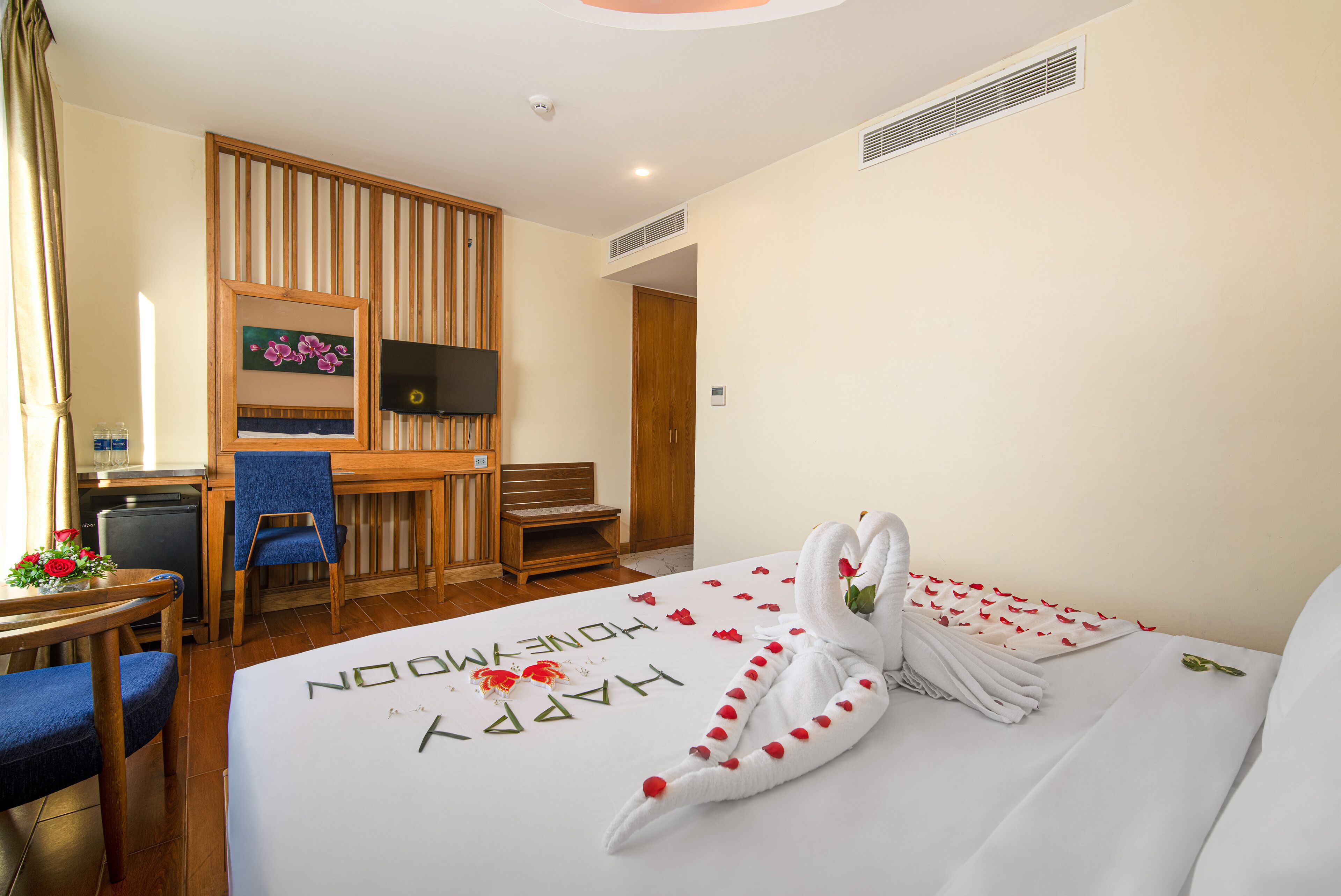 Een hotelkamer met een bed, een bureau, een stoel, een televisie en een kleine kitchenette.
