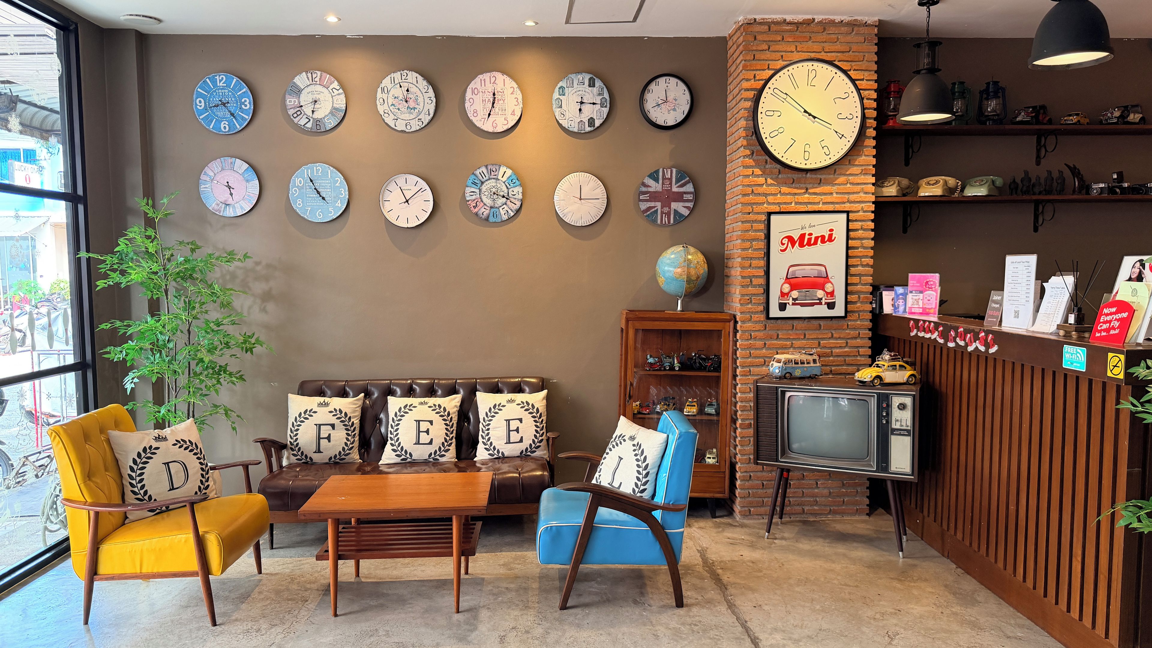 Un intérieur chaleureux avec un canapé, des fauteuils, une table basse et un mur décoré d’horloges.