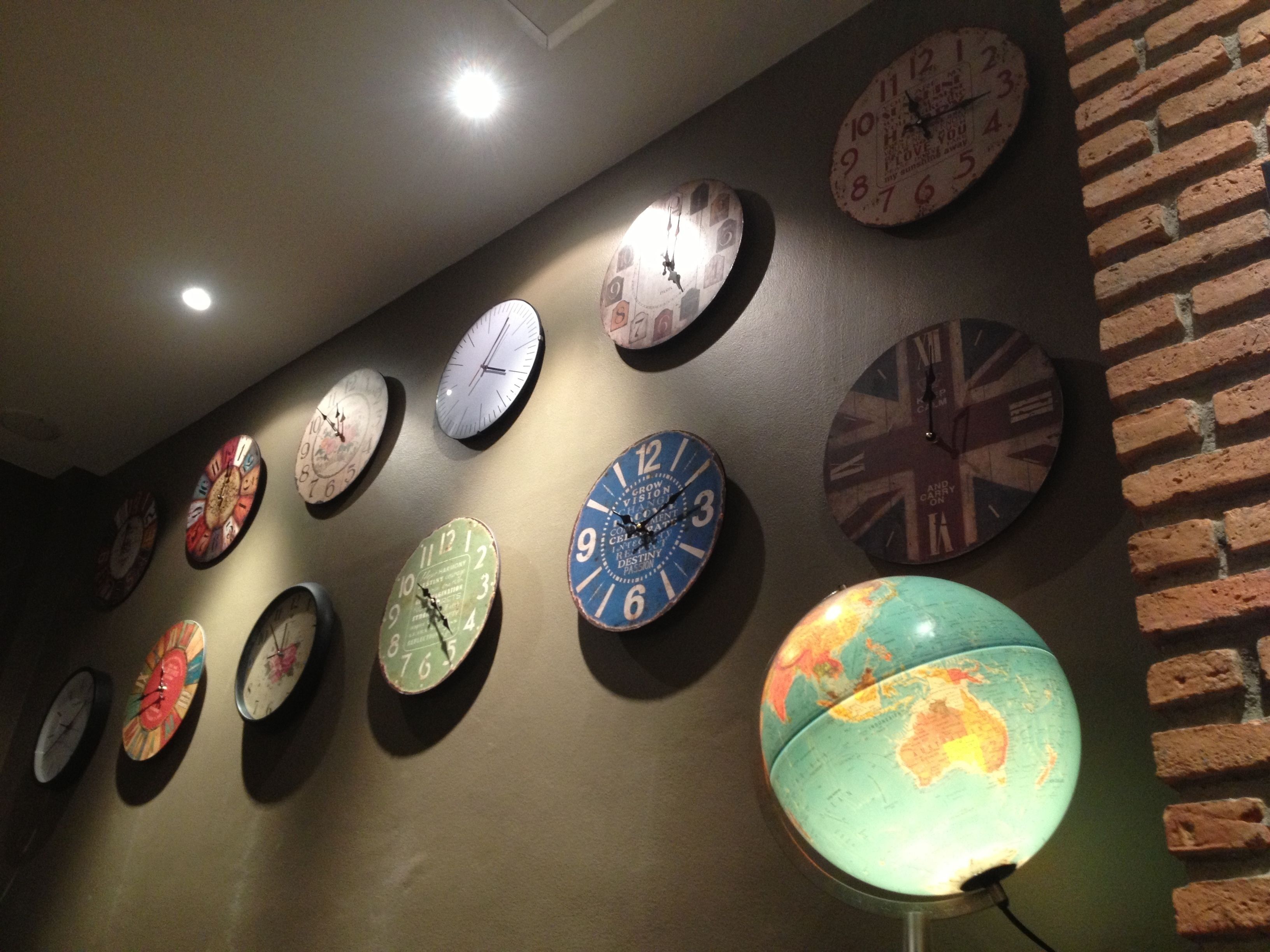 A wall with multiple clocks and a globe.