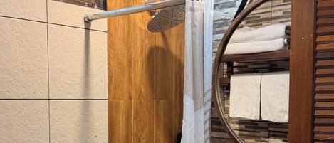 A bathroom with a wooden wall, a shower curtain, a sink, and a mirror.