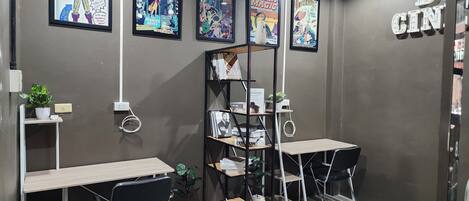 A modern room with two desks, chairs, a bookshelf, and framed comic books on the wall.