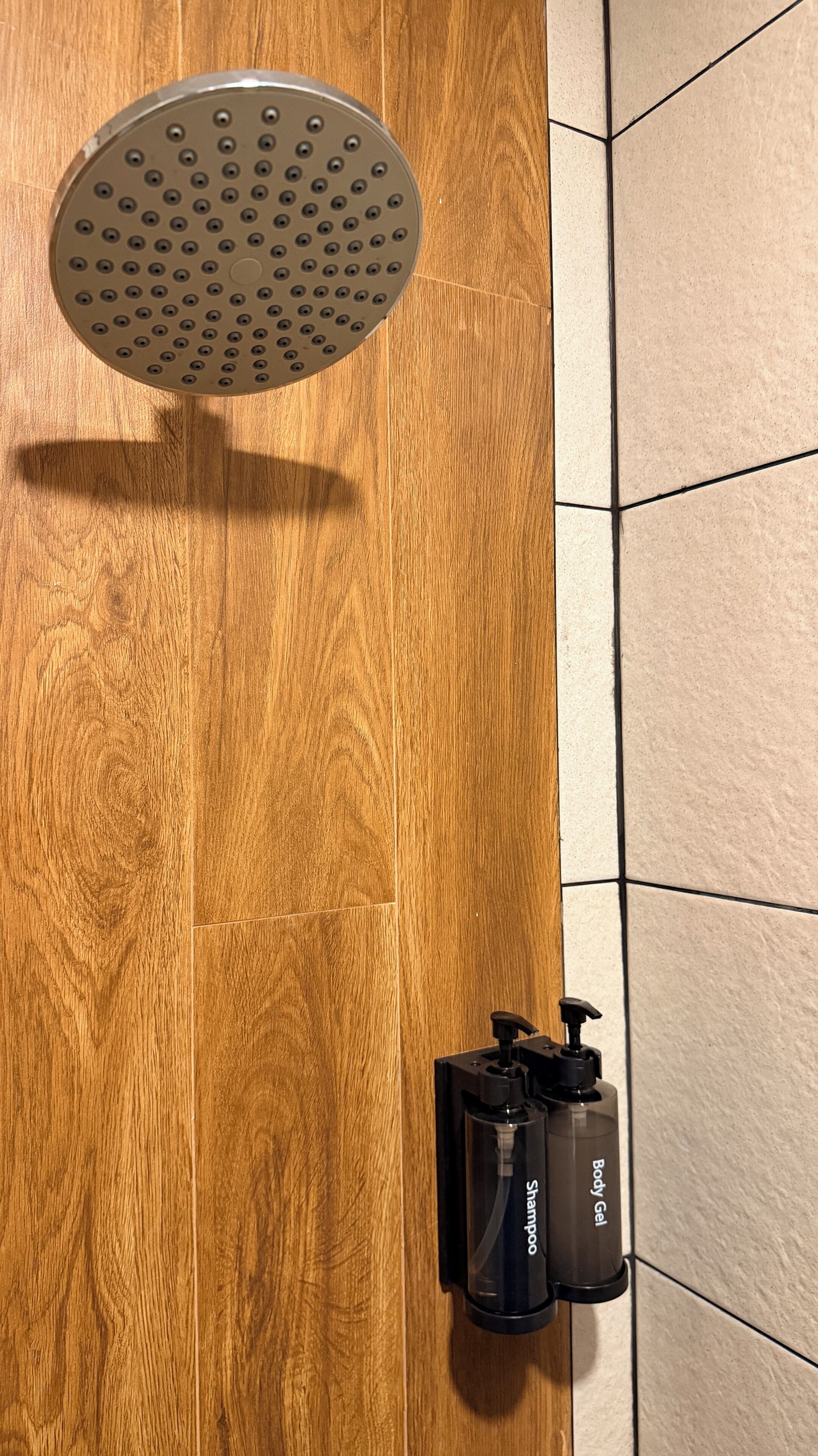 Un pommeau de douche et une bouteille de shampoing sur un plancher en bois.