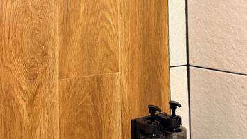 Un pommeau de douche et une bouteille de shampoing sur un plancher en bois.