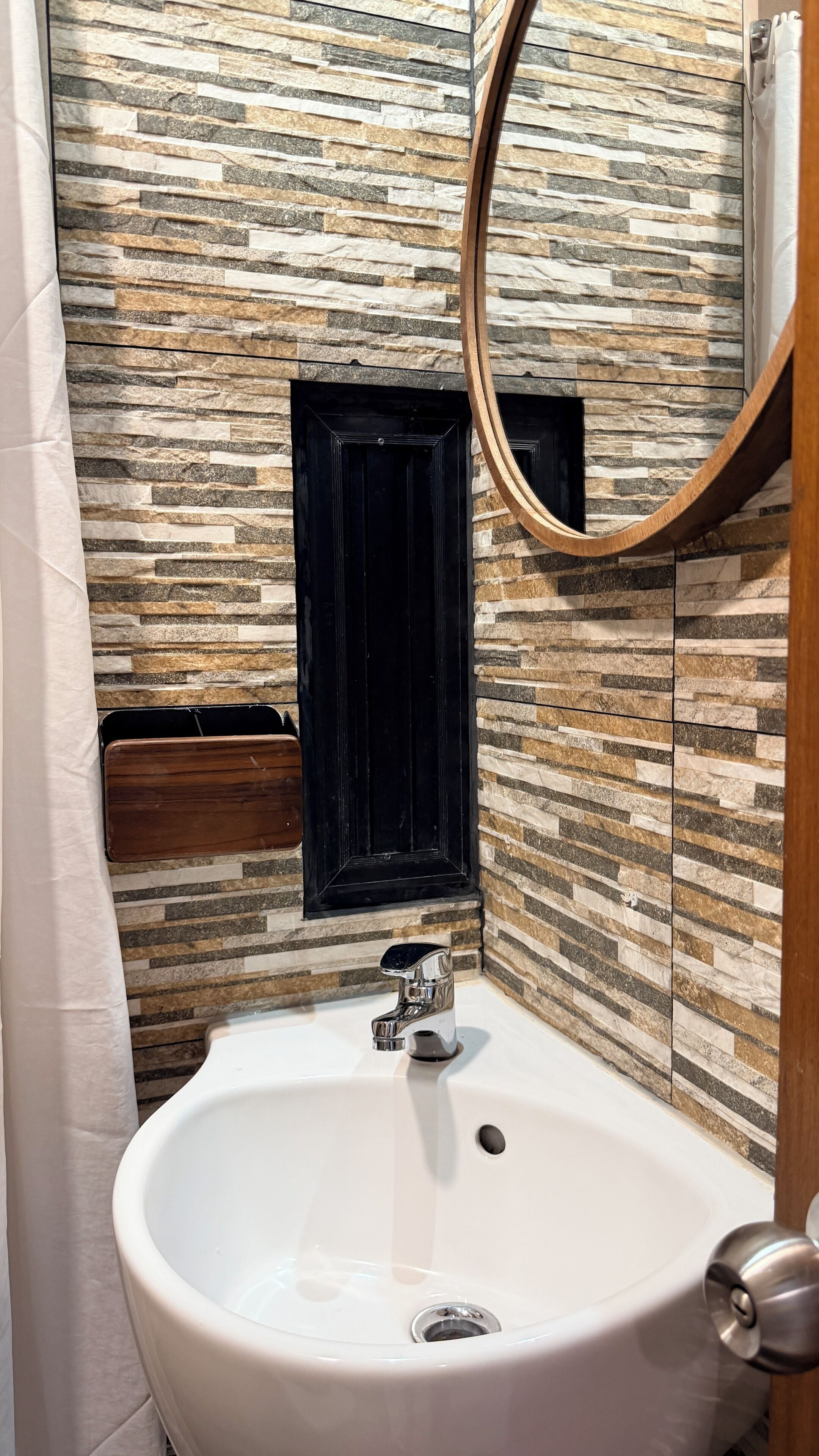 A bathroom with a white sink, a black cabinet, and a mirror.