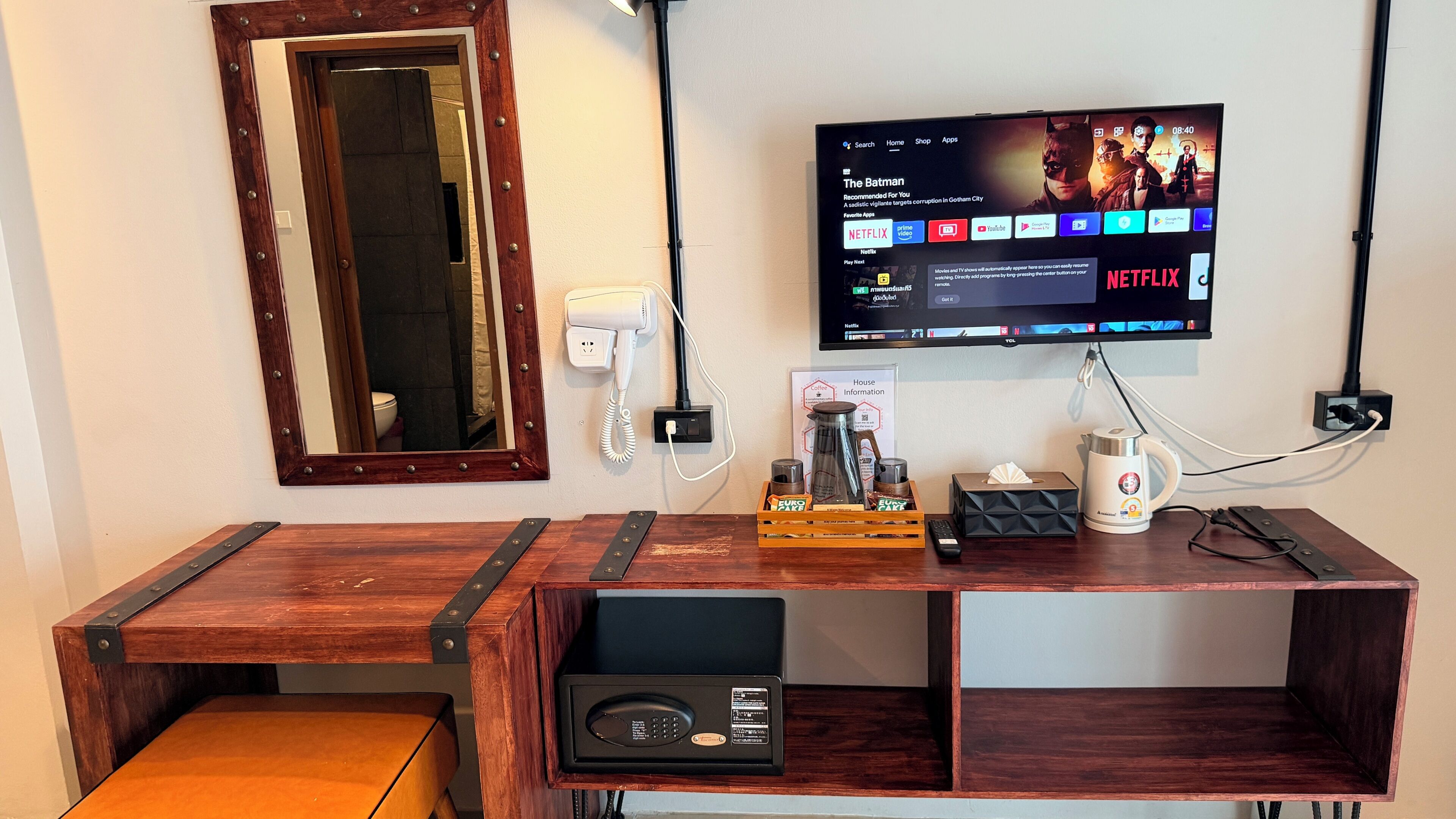A wooden desk with a flat-screen TV mounted on the wall displaying a Netflix interface.
