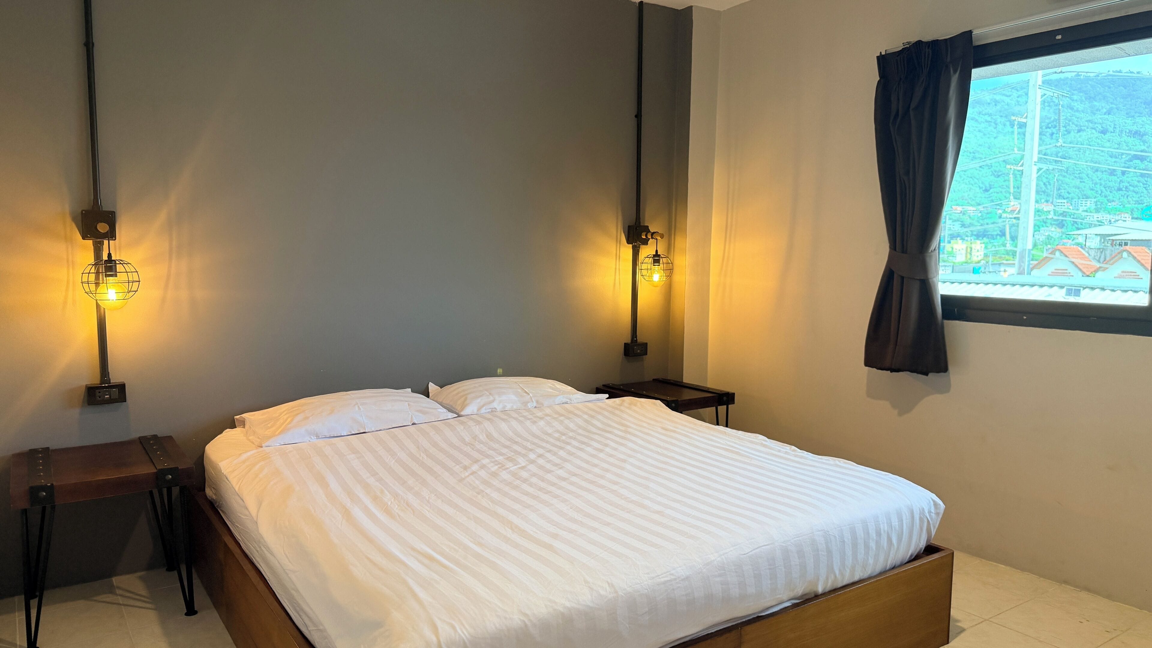 A neatly made bed with a wooden headboard in a room with two bedside tables, each with a lamp.