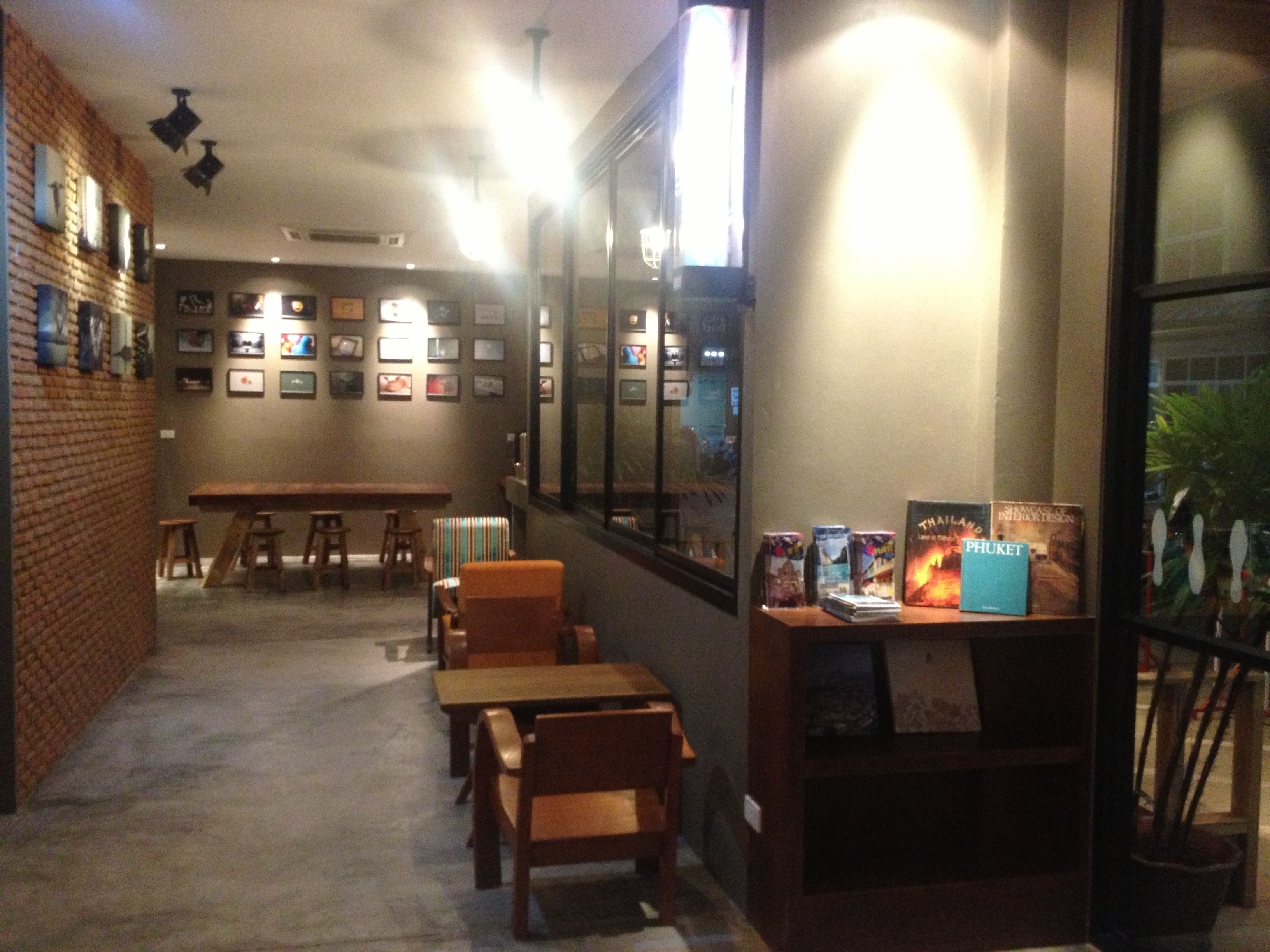 A cozy restaurant with brick walls, wooden tables, and chairs. There are framed pictures on the walls and a window with a view.