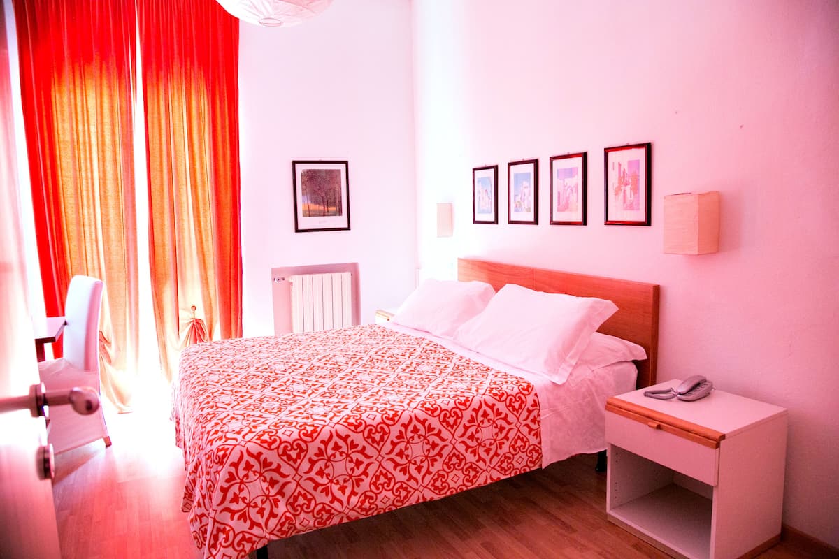 A hotel room with a bed, bedside table, and a chair.
