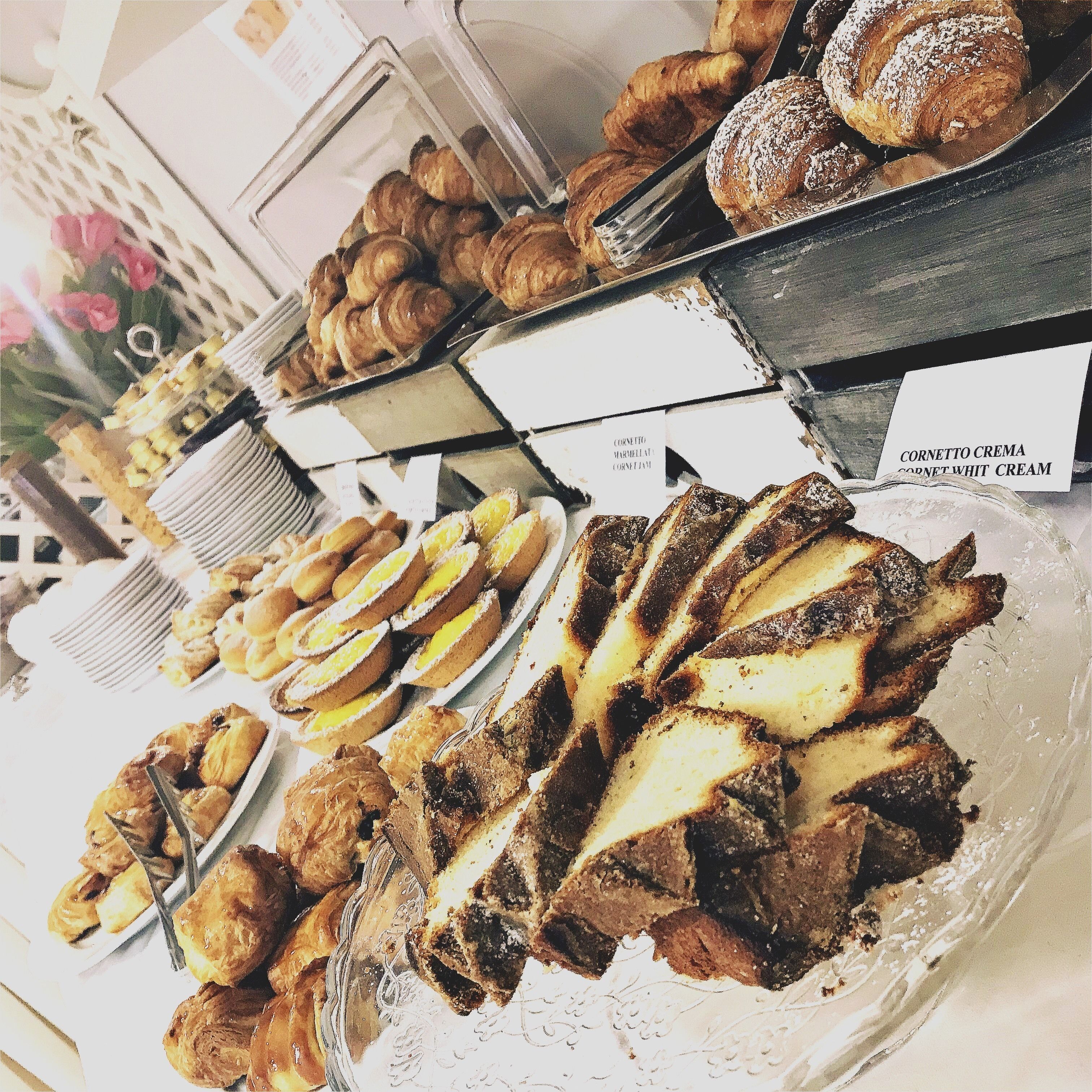 A variety of pastries and desserts displayed on trays with labels indicating different types of cream.