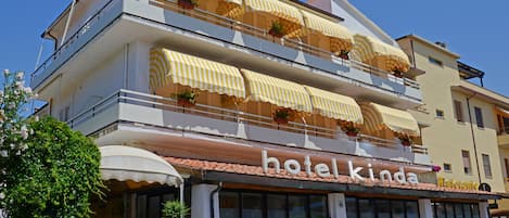 A hotel with a balcony, outdoor seating, and a sign reading "hotel kinda."