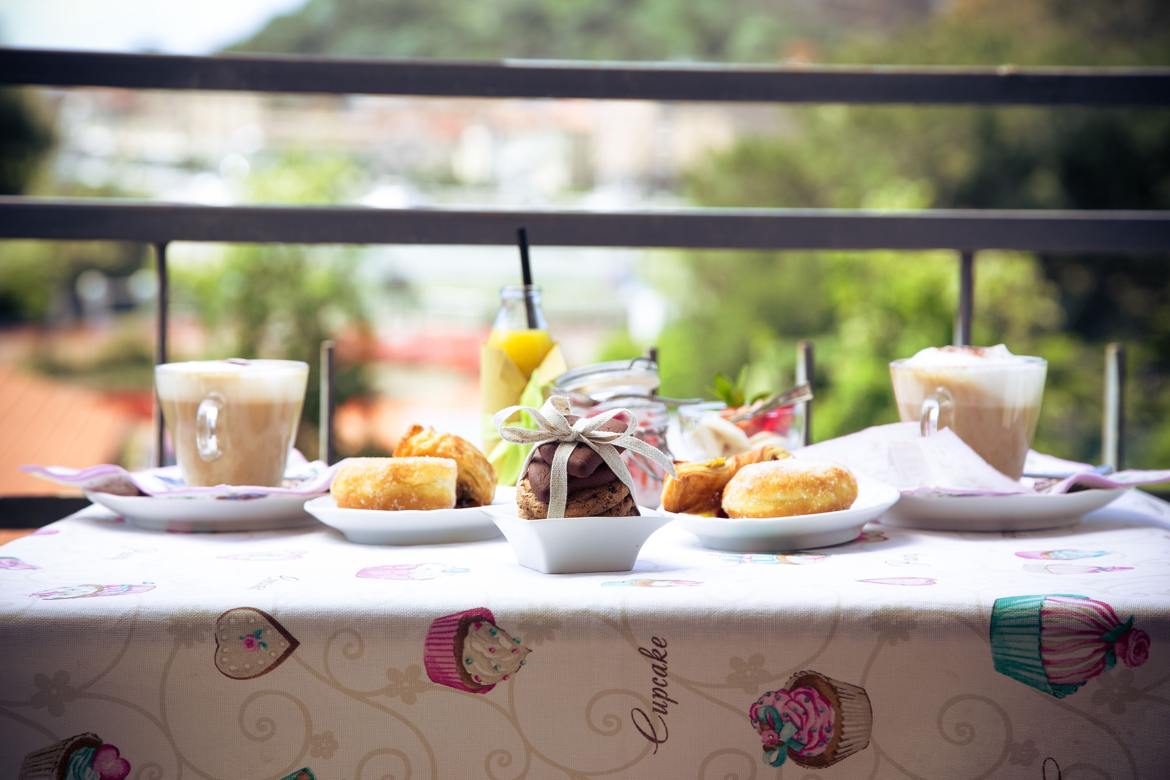 Ein Tisch mit einer Tischdecke mit Cupcake-Motiv, einer Kaffeetasse und Gebäck.