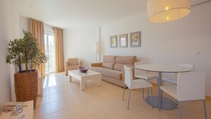 A modern living room with a sofa, a coffee table, a dining table with chairs, a potted plant, and a lamp. - Can Salia (Sant Josep de sa Talaia)