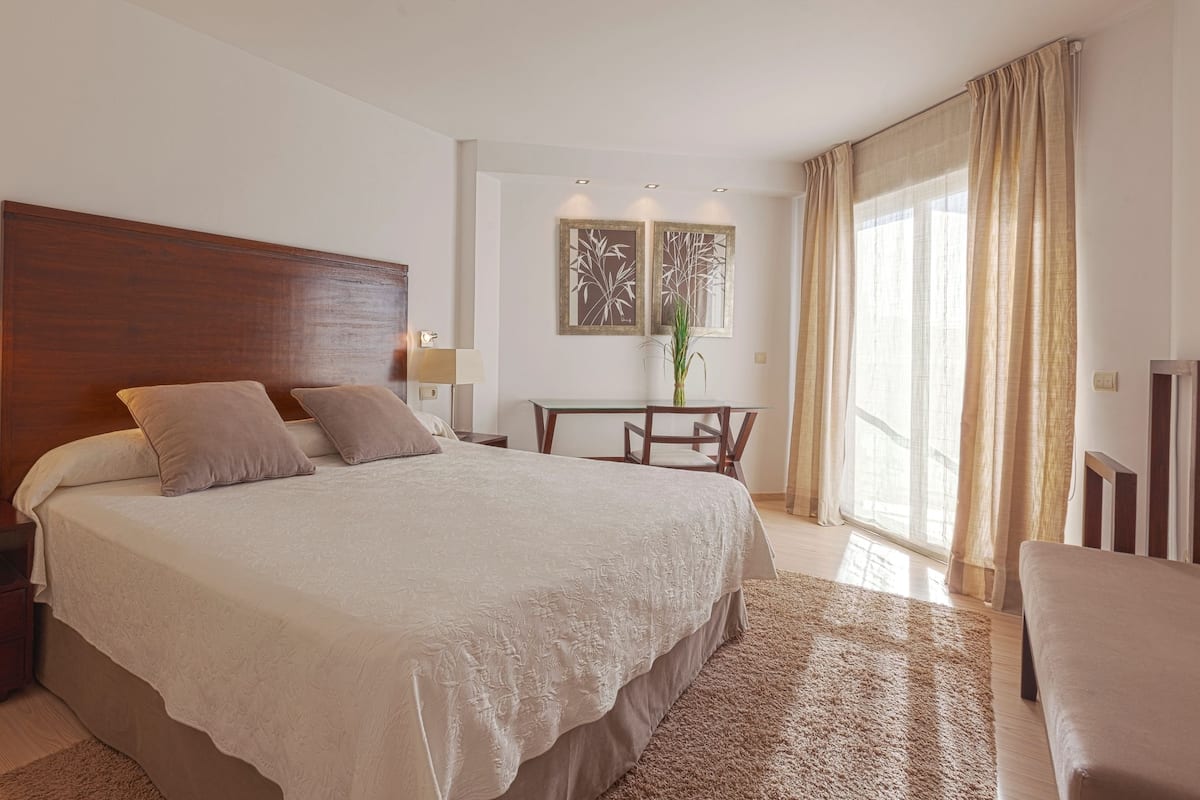 Ein Hotelzimmer mit einem großen Bett, Nachttischen, einem Schreibtisch und einem Stuhl.