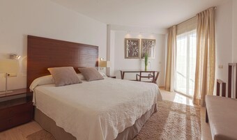 Una habitación de hotel con una cama grande, mesitas de noche, un escritorio y una silla.